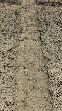 Walking on footpath between garden beds with footprints in loose soil.