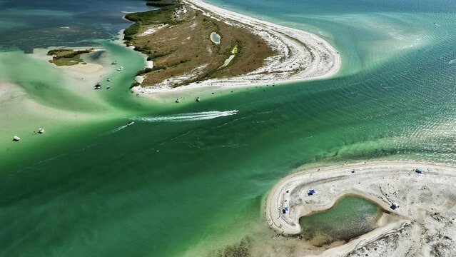 Aerial view of Honeymoon Island State Park featuring turquoise waters, white sandbars, and boats cruising through the channel in Dunedin, Florida, United States.