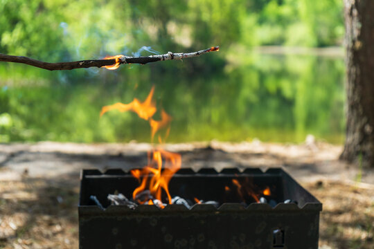 Testing fire for charcoal barbecue grill beside peaceful lake