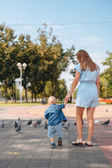 Fototapeta premium Mother and son with pigeons in city square