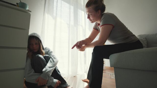Mother scolding sad teenage daughter in room