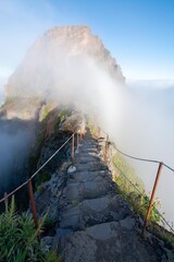 Fototapeta premium Narrow mountain trail between Pico do Arieiro and Pico Ruivo on Madeira Island, Portugal. Scenic hiking path overlooking a deep valley filled with inversion clouds and mist.