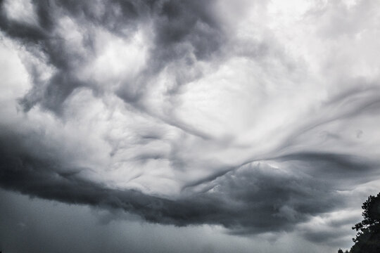 Dramatic Swirling Storm Clouds Forming Across A Darkened Atmospheric Sky