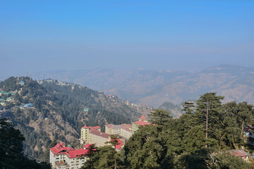 Fototapeta premium Sprawling hillside settlement with diverse rooftop styles is layered against a backdrop of hazy mountain ranges perfect for urban growth, community living, high-altitude housing, human adaptation