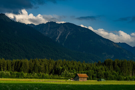 mount Entschenkopf in the Allg&auml;u Alps during summer - a small wooden hut can be seen in the valley in front of it, it is illuminated by evening sunlight