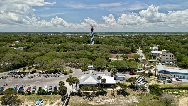 Aerial view of the St. Augustine Lighthouse with its black and white spiral stripes rising above the green canopy of Anastasia Island in St. Johns County, Florida, United States.