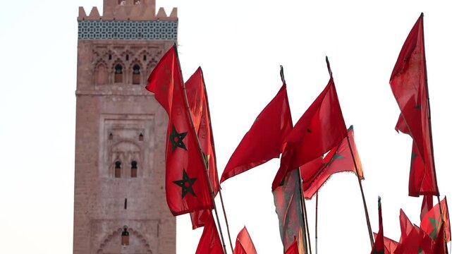 slow motion of Moroccan national flags with Koutoubia tower in the background