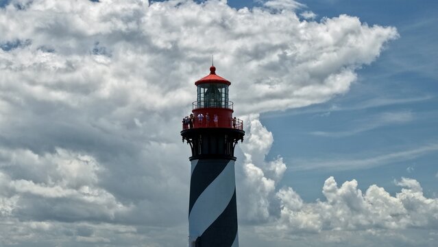 Aerial view of the St. Augustine Lighthouse on Anastasia Island with people on the observation deck under a cloudy sky in St. Johns County, Florida, United States.