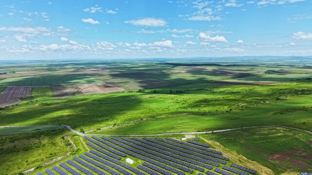 Aerial view solar panel field stretching across rolling green hills, sunlit prairie patches, distant horizon and scattered access tracks, site planner