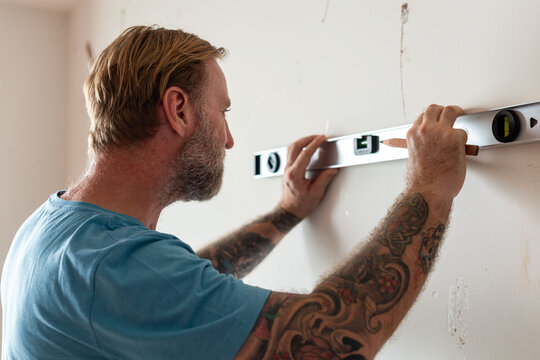Tattooed man using level tool