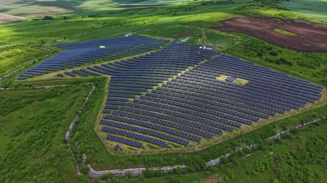 Aerial closeup solar panels array sweeping hillside with dense module rows, visible access lanes and inverter pads, operations manager inspection viewpoint