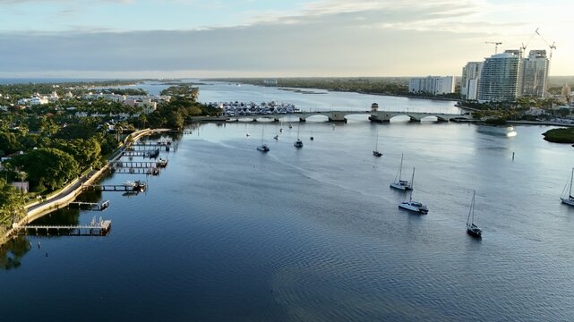 Aerial view of the Intracoastal Waterway with sailboats, the Flagler Memorial Bridge, and the city skyline under a soft morning light West Palm Beach, Florida, United States.