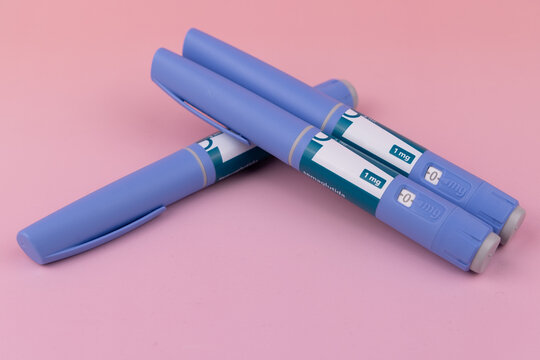 Multiple semaglutide glp1 injector pens stacked in a pyramid shape for type 2 diabetes and obesity treatment on pink background.