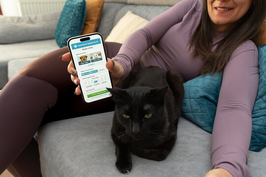 Woman using smartphone veterinary app booking cat appointment