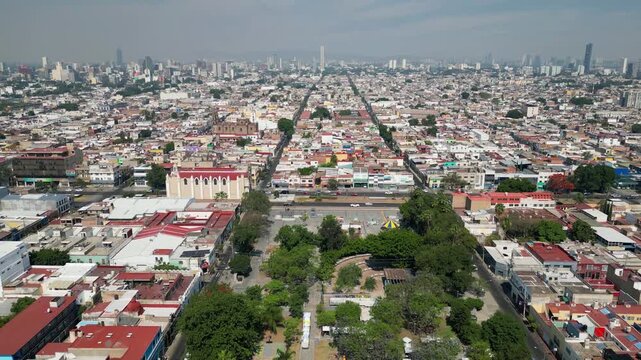 Dynamic drone view flying forward above Guadalajara city. Showcases the urban landscape with Refugio Park, buildings, and streets.
