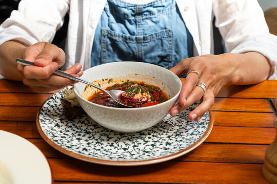 Cropped view of a person eating traditional borscht soup with sour cream and dill