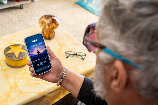 Senior adult using smartphone for mindfulness meditation podcast