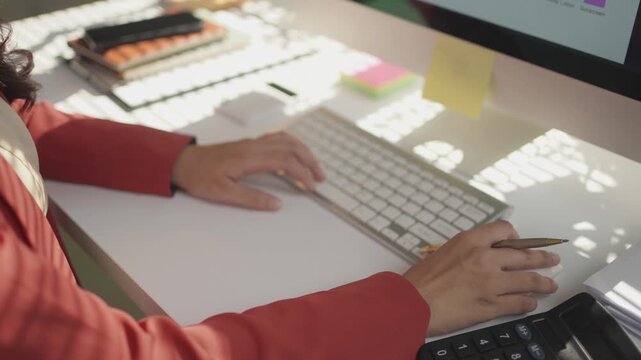 Close up of professional female accountant hands typing on a wireless keyboard. Financial analyst working on a computer in a sunny office