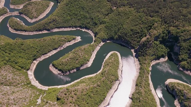 4K cinematic drone shot of the spectacular Uvac River meanders canyon in Serbia. Aerial footage of curvy river winding through deep rocky cliffs and green hills.