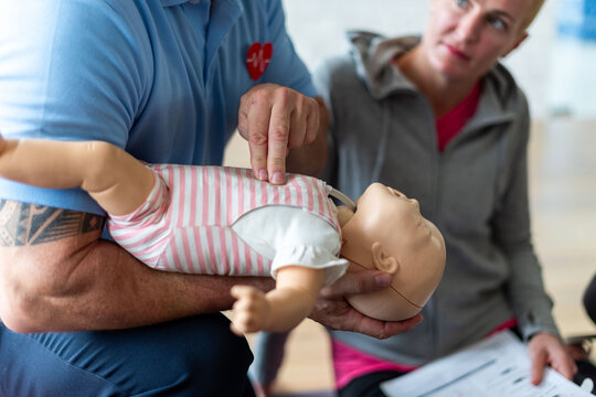 Person demonstrating CPR on a baby mannequin during a training session.
