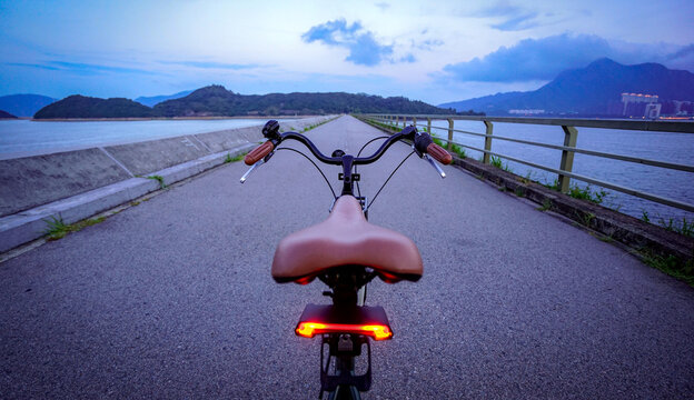 Riding a bicycle on a scenic coastal path at dusk with mountains in the background