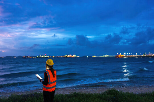 Asian female engineer assessing offshore Energy resources at sunset, advancing Industry excellence, Oil production efficiency, Refinery technology, and digital operations.