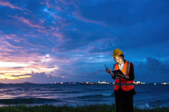 Asian female engineer utilizing smart technology for offshore Energy operations, promoting Industry advancement, Oil logistics management, Refinery excellence, AI monitoring, and operational safety.