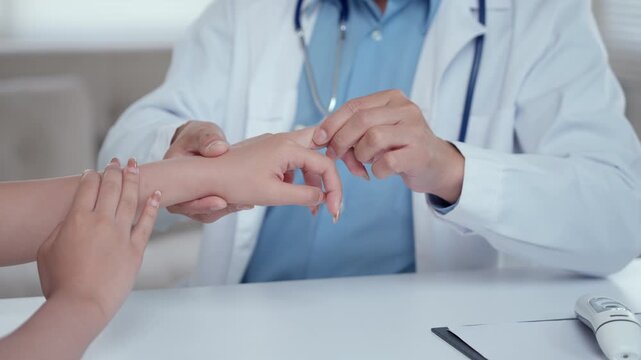 Medical professional palpating a female patient's hand and wrist to diagnose joint pain, arthritis, or carpal tunnel syndrome