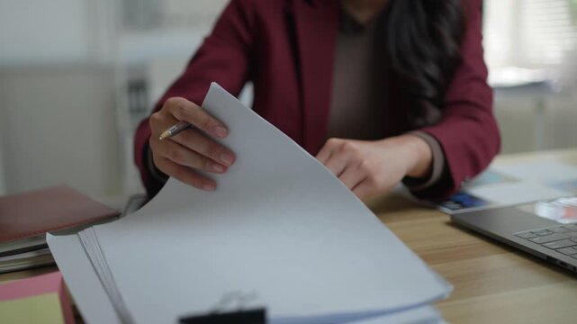Unrecognizable businesswoman hands flipping through a stack of paper documents. Professional manager looking for files at the office desk