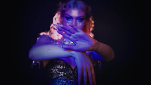 Portrait blurred silhouette face fashion model posing dancing waving body hand, woman shiny art make up rhinestones glitter dress. blue pink purple neon light teen girl in slow motion close-up hands