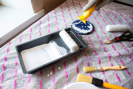 Hand dipping roller into paint tray. Self made home improvement on budget. Cosmetic renovation
