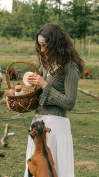 Young woman holding a basket of goat milk products in a pastoral setting