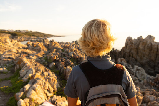 barefoot pre teen boys climbing and exploring rocky coastline of DeKelders, South Africa