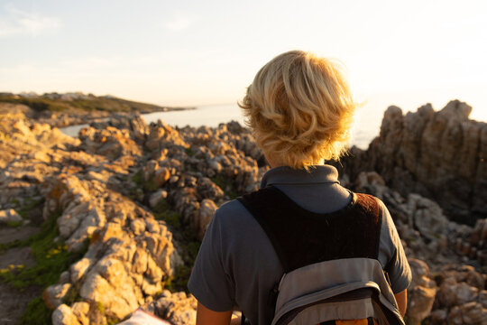 barefoot pre teen boys climbing and exploring rocky coastline of DeKelders, South Africa