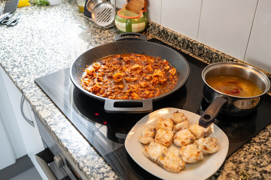 Preparing seafood paella with monkfish on induction hob