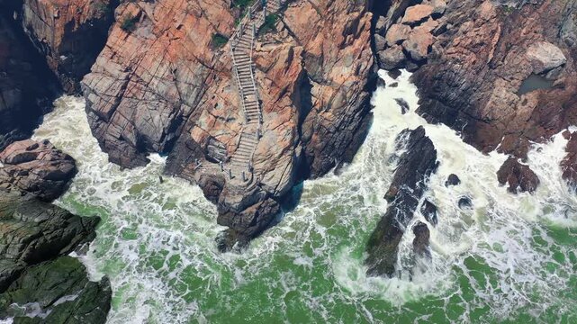 Aerial View of Stone Stairs on Rocky Coastline Above Crashing Ocean Waves