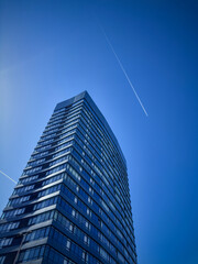 Obraz premium Modern glass skyscraper rising into a clear blue sky