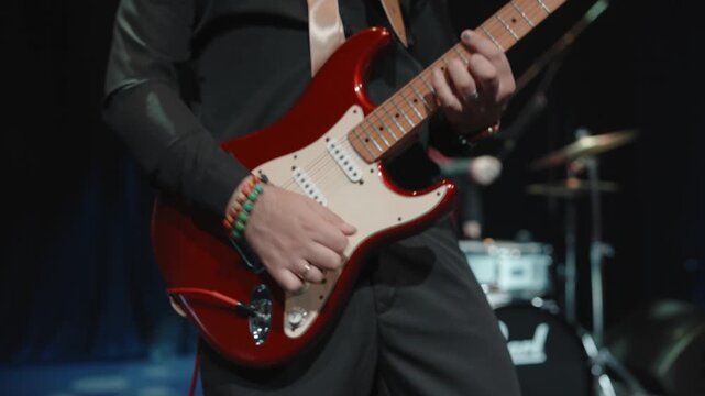 Talented female guitarist performing live on stage, singing while playing guitar under dramatic concert lighting.