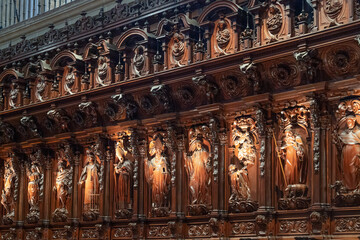 Obraz premium Close-up view of the intricate and ornate Baroque dark wood carvings inside the Cathedral of Malaga, Spain. The masterfully sculpted religious figures and saints decorate the historic choir stalls.