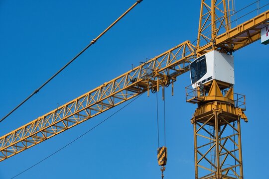 Yellow tower crane cabin and jib arm against a clear blue sky