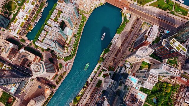 Thriving Chicago downtown from drone footage. Vessels move slowly by the blue Chicago River. Multiple cars run by the highways.