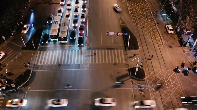Aerial Night View of Busy City Intersection with Cars and Scooters