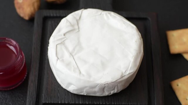 Pink Brie or Camembert cheese with honey, jam, figs, and crackers for a hearty breakfast. Brie cheese as a food background for your design