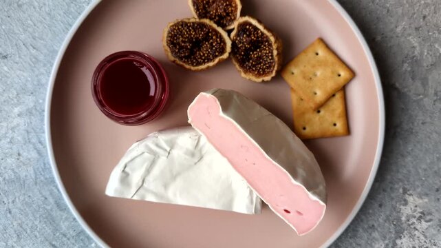 Pink Brie or Camembert cheese with honey, jam, figs, and crackers for a hearty breakfast. Brie cheese as a food background for your design