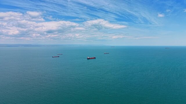 Few cargo ships on the vast turquoise waterscape. Vessels on the roadstead heading to the port. Aerial view.