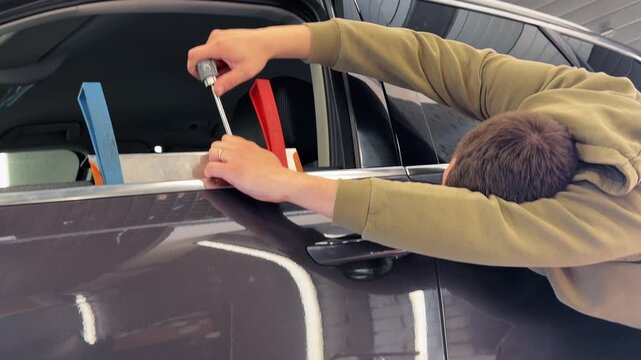 PDR. The mechanic at the auto shop with tools to repair dents in car body. Body repair. A specialist repairs a dent on the car body without painting. Paintless Car Dent Repair. 