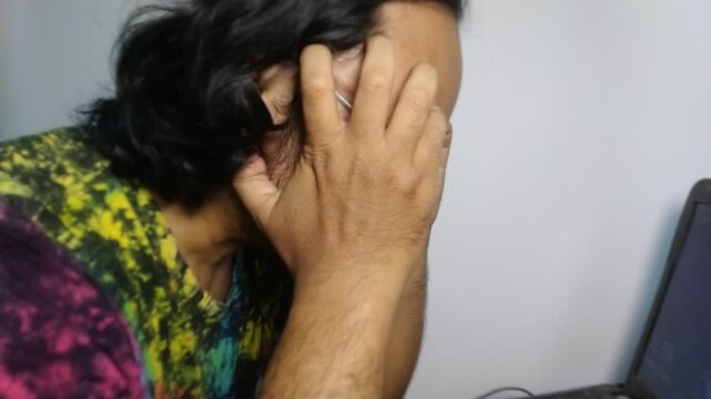 Stressed freelance designer holding her head in hands in front of laptop.