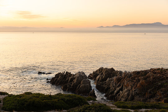 2 pre teen boys climbing and exploring the rocky coastline of DeKelders, South Africa