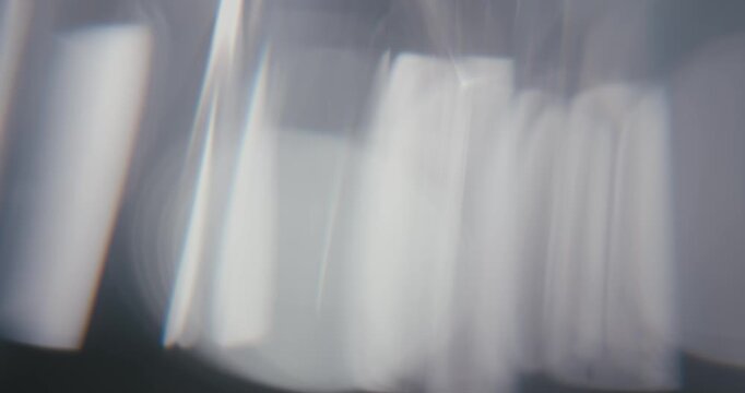 Abstract gray background with moving lens flares and refractions. Delicate colors bokeh effect for luxury logo display. Grey-blue light leaks on a blurred background with copy space. 