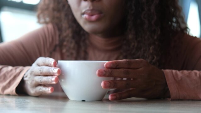 Women's hands hold a mug of hot tea in the morning during the cold season. A young woman warms her hands on a very hot cup of tea.